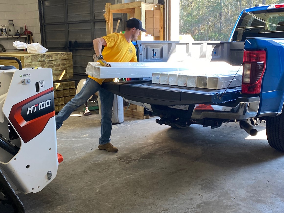 Photo of a fence installer loading a truck bed with vinyl fence material